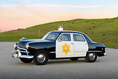AUT 20 RK0667 01
1949 Ford Police Car 3/4 Side View On Pavement By Grassy Hills At Dusk