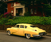 AUT 20 RK0101 02
1948 Tucker Yellow 3/4 Rear View On Pavement By Green Plants And House