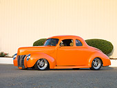 AUT 20 RK0372 01
1940 Ford Deluxe Coupe Orange 3/4 Front View On Pavement By Fence