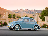 AUT 21 BK0033 01
1957 Volkswagen Beetle Light Blue 3/4 Side View On Pavement By Gate And Hills