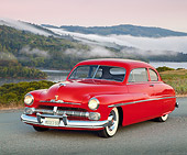 AUT 21 RK0324 01
1950 Red Mercury 3/4 Front View On Pavement Headlights On By Grass At Dusk