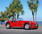 AUT 21 RK1121 02
1954 Curtis 500S Roadster Red Low 3/4 Side View On Pavement By Palm Trees And Water Blue Sky