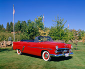 AUT 21 RK1566 02
1952 Ford Sunliner Convertible Red 3/4 Front View On Grass By Trees And Bushes Blue Sky