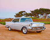 AUT 21 RK2832 01
1957 Chevrolet Bel Air Silver 3/4 Front View On Sand By Trees And Houses At Dusk