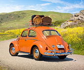 AUT 21 RK3031 01
1958 VW Bug Sedan Coral Red With Luggage 3/4 Rear View On Pavement By Grassy Hills