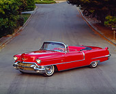 AUT 21 RK0336 05
1956 Red Cadillac Convertible 3/4 Side On Road By Grass And Trees Headlights On