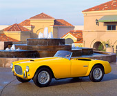 AUT 21 RK0375 06
1952 Yellow Siata Spyder Convertible 3/4 Side View On Pavement By Fountain And Buildings