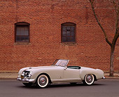AUT 21 RK0406 01
1953 Nash-Healey Roadster Gray 3/4 Front View On Pavement By Brick Building, Windows And Bare Tree