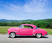 AUT 21 RK0411 04
1951 Custom Pink Chevrolet Side View On Pavement By Grass And Hills Blue Sky