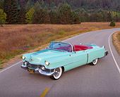 AUT 21 RK0808 01
1954 Cadillac Convertible Light Green 3/4 Front View On Road Headlights On By Dry Grass And Trees