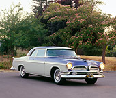 AUT 21 RK0897 03
1955 Chrysler New Yorker Blue And White 3/4 Front View On Pavement By Pink Blossom Tree Headlights On