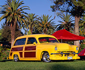 AUT 21 RK0901 01
1951 Ford Woody Wagon Yellow Wood Panel Low 3/4 Side View On Grass Palm Trees Blue Sky