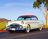 AUT 21 RK0947 02
1954 Packard Pacific Red And White 3/4 Front View On Road By Bushes Blue Sky