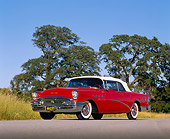 AUT 21 RK0996 04
1955 Buick Roadmaster Convertible Red Low 3/4 Side View On Pavement By Trees Blue Sky