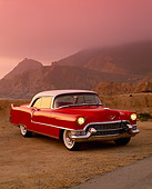 AUT 21 RK1305 02
1955 Cadillac Coupe Red And White 3/4 Front View On Sand Rock Mountains Fog Red Filtered