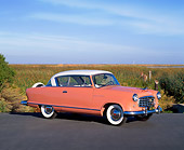 AUT 21 RK1389 04
1955 AMC Nash Rambler Country Club Pink 3/4 Side View On Pavement Blue Sky
