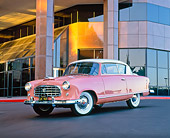 AUT 21 RK1394 03
1955 AMC Nash Rambler Country Club Pink 3/4 Front View On Pavement By Building