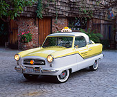 AUT 21 RK1418 09
1956 Nash Metropolitan Taxi Yellow And White 3/4 Front View On Pavement By House