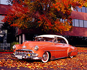 AUT 21 RK1854 01
1952 Chevrolet Deluxe Salmon And White Low 3/4 Front View By Autumn Tree And Building