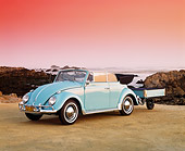 AUT 22 RK1154 04
1962 VW Karmann Convertible Blue With Trailer 3/4 Front View On Sand By Rocks And Water Pink Sky