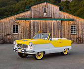 AUT 22 RK3168 01
1960 Nash Metropolitan Yellow And White 3/4 Front View On Pavement By Old Barn