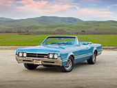 AUT 22 RK3173 01
1966 Oldsmobile 442 Light Blue 3/4 Front View On Gravel By Grass Field And Hills