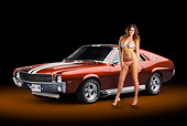 AUT 22 RK3368 01
1969 AMC AMX Candy Tangerine With White Stripes 3/4 Front View In Studio With Swimsuit Model