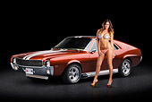 AUT 22 RK3374 01
1969 AMC AMX Candy Tangerine With White Stripes 3/4 Front View On Pavement With Swimsuit Model