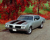 AUT 22 RK0141 07
1969 Oldsmobile 442 Silver Black Stripe 3/4 Front View On Pavement By Fall Trees