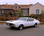 AUT 22 RK0957 04
1969 Oldsmobile Hurst 455 White And Gold 3/4 Side View On Pavement By House