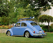 AUT 22 RK1206 04
1964 Volkswagen Beetle Light Blue With Surfboard 3/4 Rear View On Grass By Flowers And Trees