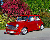AUT 22 RK1915 06
1961 Austin Mini Cooper Modified Orange 3/4 Front View On Pavement By Bushes