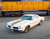 AUT 23 BK0039 01
1973 Oldsmobile Cutlass White And Gold Stripe 3/4 Front View On Gravel By Train