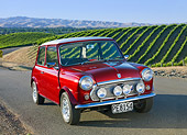AUT 23 BK0053 01
1975 Morris Mini 1000 Red 3/4 Front View On Road By Crops