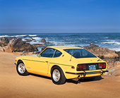 AUT 23 RK0367 04
1971 Datsun 240Z Sport Yellow 3/4 Rear View On Sand By Ocean And Rocks