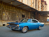 AUT 23 RK2012 01
1970 Plymouth Road Runner Hemi Blue With Black Stripe 3/4 Front View On Pavement By Old Factory Building