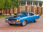 AUT 23 RK2018 01
1970 Plymouth Road Runner Hemi Blue With Black Stripe 3/4 Front View On Pavement By Building