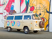 AUT 23 RK2156 01
1974 Volkswagen Type 2 Tan With Hippie Logos 3/4 Side View On Pavement By Mural