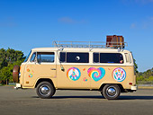 AUT 23 RK2160 01
1974 Volkswagen Type 2 Tan With Hippie Logos Profile View On Pavement By Trees