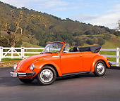 AUT 23 BK0001 01
1974 Volkswagen Cabriolet Orange Peel 3/4 Front View On Pavement By White Fence And Hills