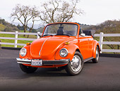 AUT 23 BK0003 01
1974 Volkswagen Cabriolet Orange Peel 3/4 Front View On Pavement By White Fence And Hills