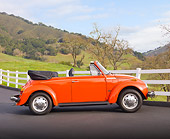 AUT 23 BK0004 01
1974 Volkswagen Cabriolet Orange Peel Profile View On Pavement By White Fence And Hills