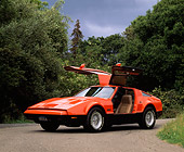 AUT 23 RK0075 05
1975 Orange And Black Bricklin 3/4 Front View Gullwing Doors On Pavement By Trees Cloudy Sky