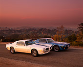 AUT 23 RK0280 02
1970 & 1971 Pontiac Trans Am Blue And White 3/4 Side View On Pavement Dark Pink Sky