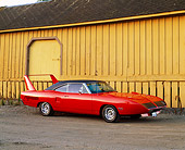 AUT 23 RK0333 04
1970 Plymouth Superbird 440 Six Pack Tor Red 3/4 Side View On Pavement By Side Of Yellow Building At Dusk