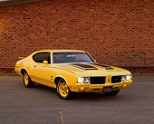 AUT 23 RK0642 01
1970 Oldsmobile Cutlass Rallye 350 Yellow And Black Front 3/4 View On Pavement By Brick Wall
