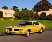 AUT 23 RK0643 03
1970 Oldsmobile Cutlass Rallye 350 Yellow And Black Front 3/4 View on Pavement By Building And Trees