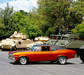 AUT 23 RK0953 02
1970 Chevy Nova Orange And Black 3/4 Side View On Pavement By Military Tanks