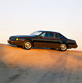 AUT 24 RK0051 01
1986 Ford Thunderbird Turbo Coupe Black 3/4 Front View On Pavement Hill At Dusk