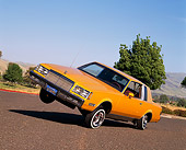 AUT 24 RK0097 09
1982 Buick Regal Lowrider Orange With Hydrolics 3/4 Front View On Pavement By Trees Blue Sky